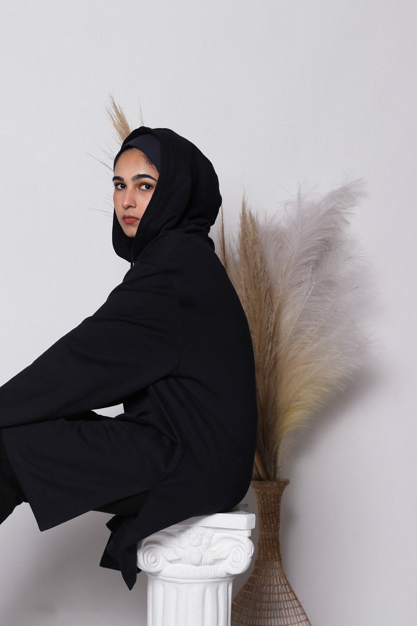 Person wearing a black hijab hoodie with white background