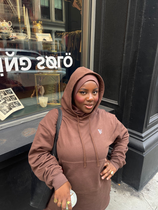 Person wearing a brown hoodie standing in front of a store window with 'FLYING SOLO' branding.